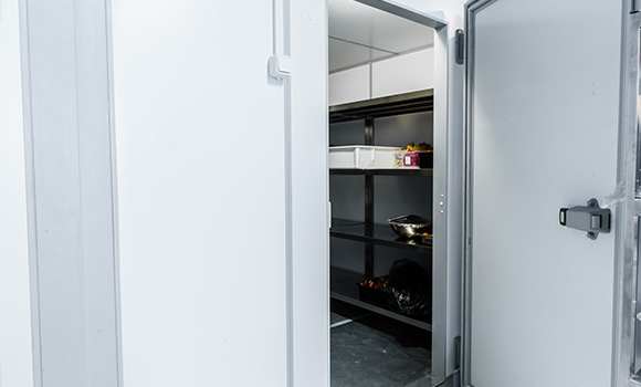 walk-in freezer with open door and empty shelves for food storage and preservation techniques in commercial settings