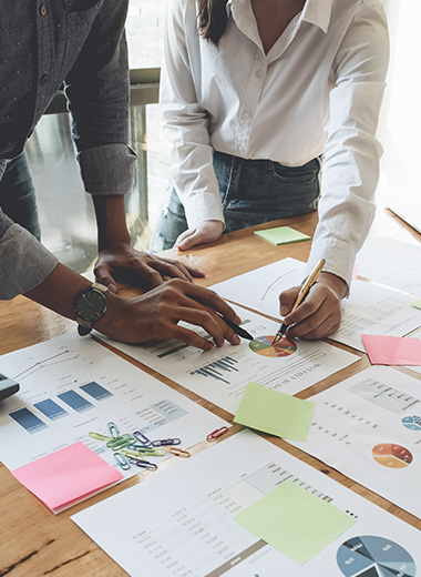people collaborating on business charts and data analysis using colored sticky notes and graphs for effective planning and presentation 2 strategies 2 teams